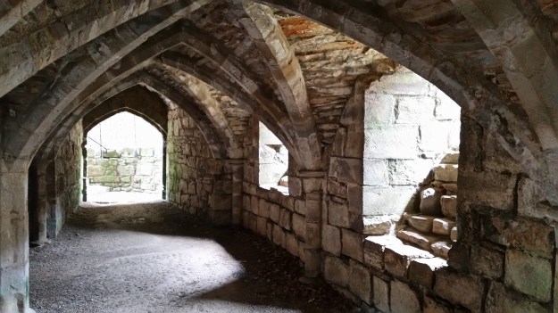 Interior of Finchdale Priory, stone with pointed arches, sunshine coming in from windows and door.